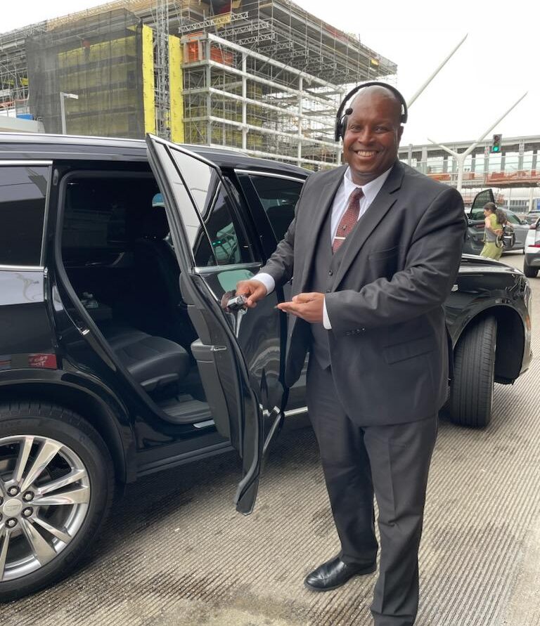 Thousand Oaks Airport Shuttle Service. Owner Patrick W Paige standing next to a luxury Cadillac Sedan at Tom Bradley terminal LAX